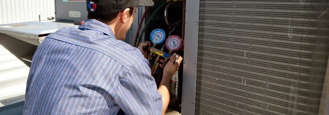 HVAC technician servicing a condenser unit in East Coventry
